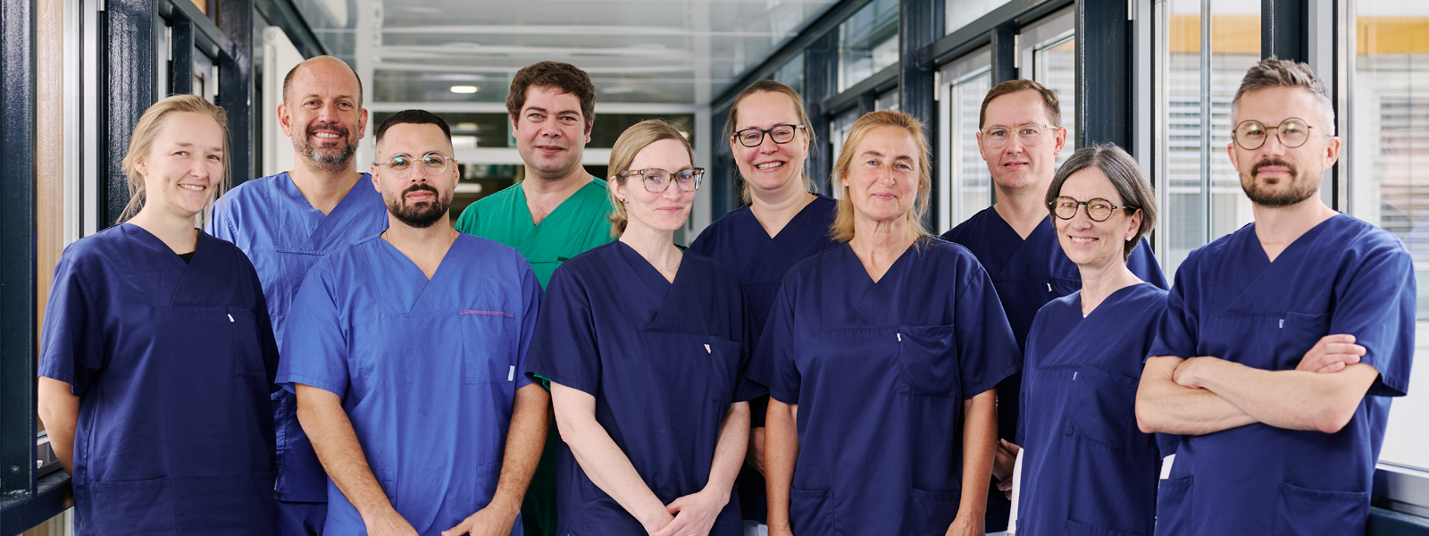 Sechs Ärzte und eine Ärztin stehen in Dienstkleidung zum Gruppenfoto zusammen