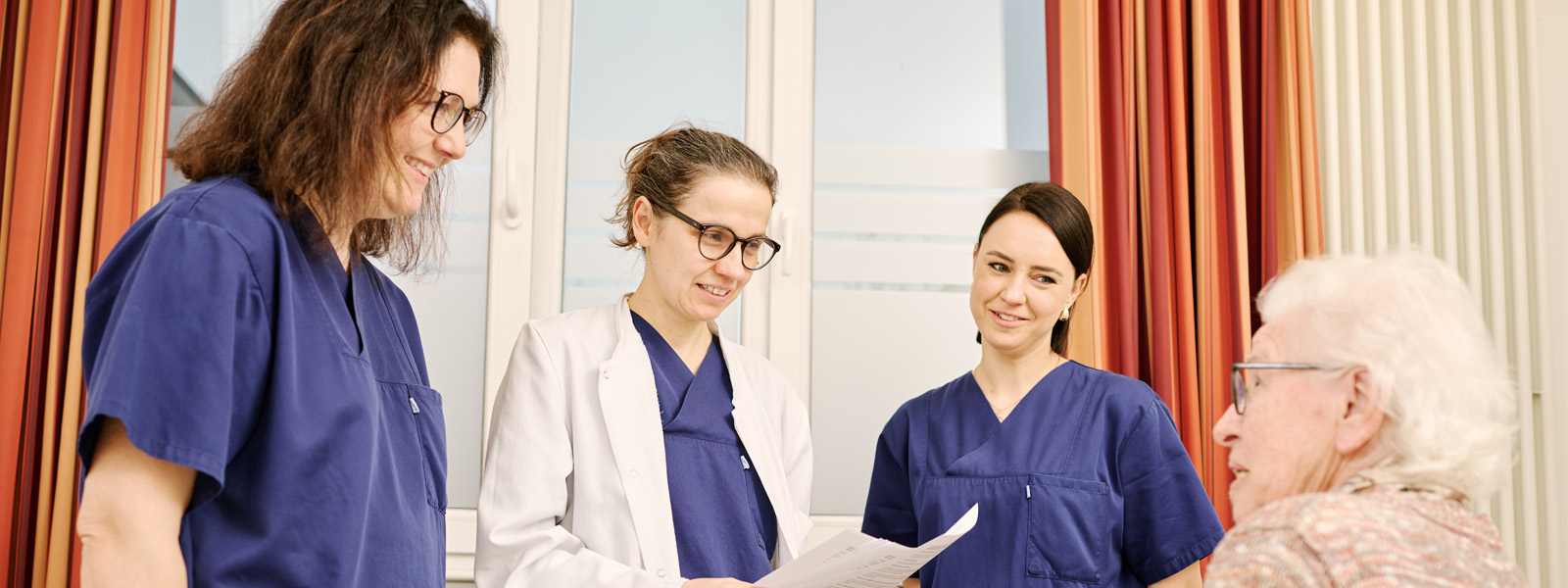 Chefärztin, Ärztin und Pflegekraft am Bett der Patientin