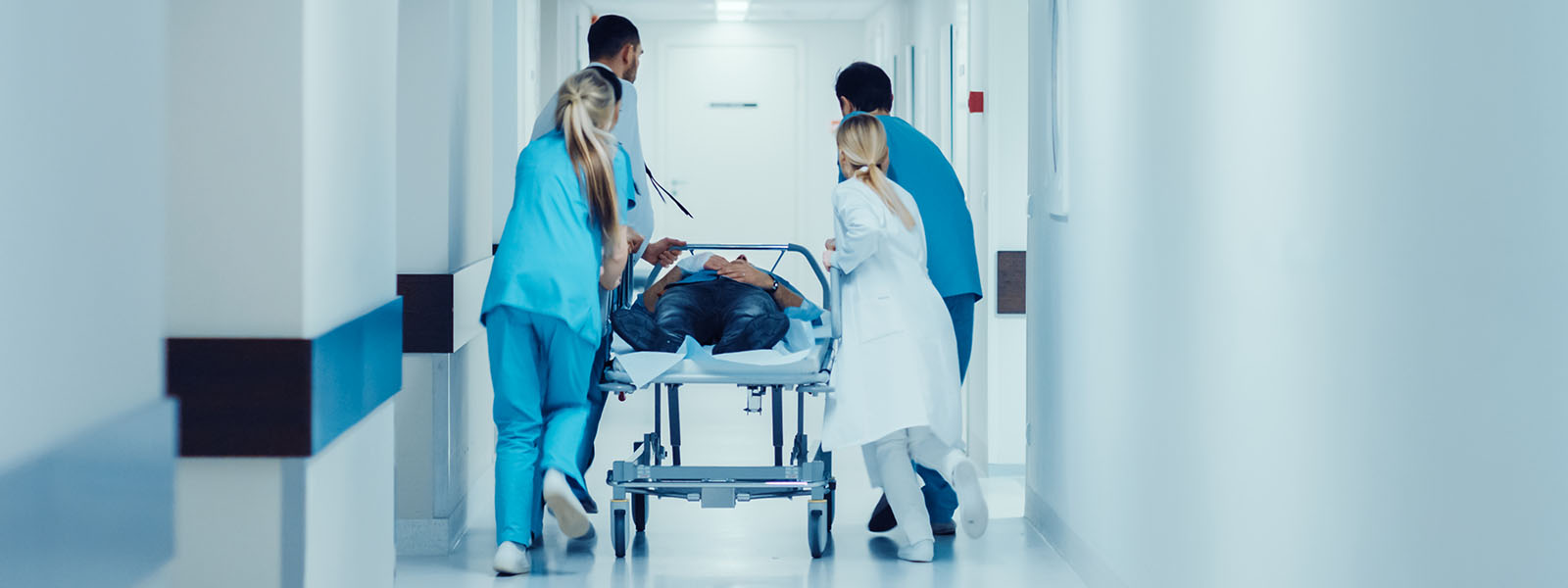 Patient wird vom Personal auf Trage durch den Flur zur Notaufnahme geschoben